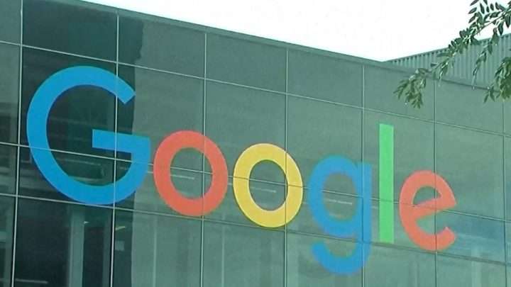 Google logo displayed on a glass-front office building facade in blue, red, yellow, and green color letters, outdoors